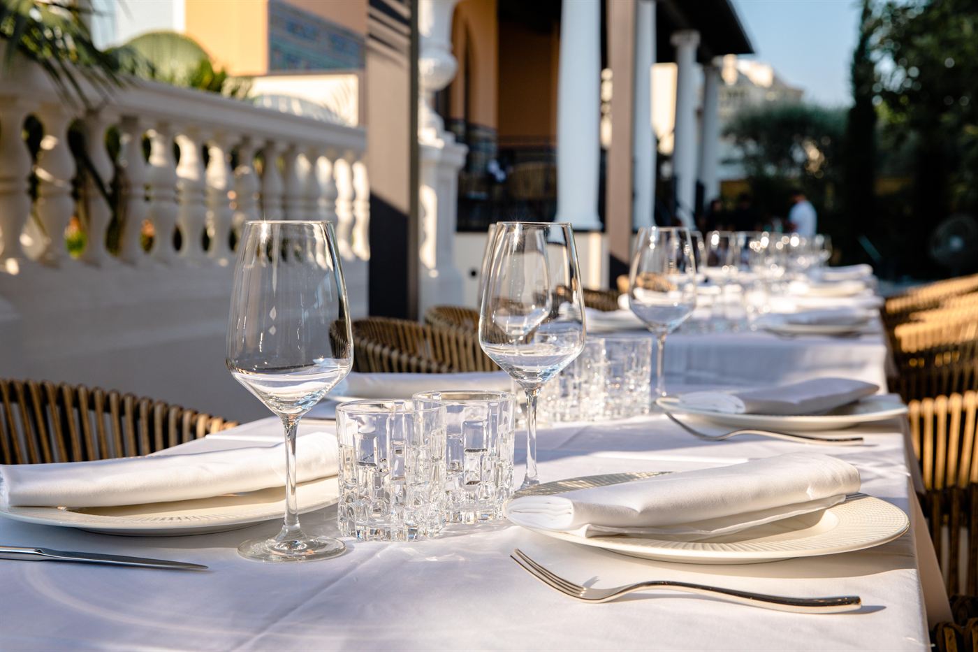 Uma mesa comprida com cristais e toalhas brancas no terraço do restaurante